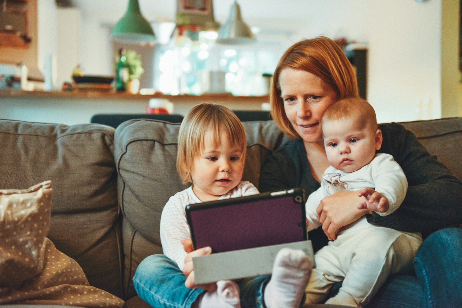 life, two babies and woman sitting on sofa while holding baby and watching on tablet